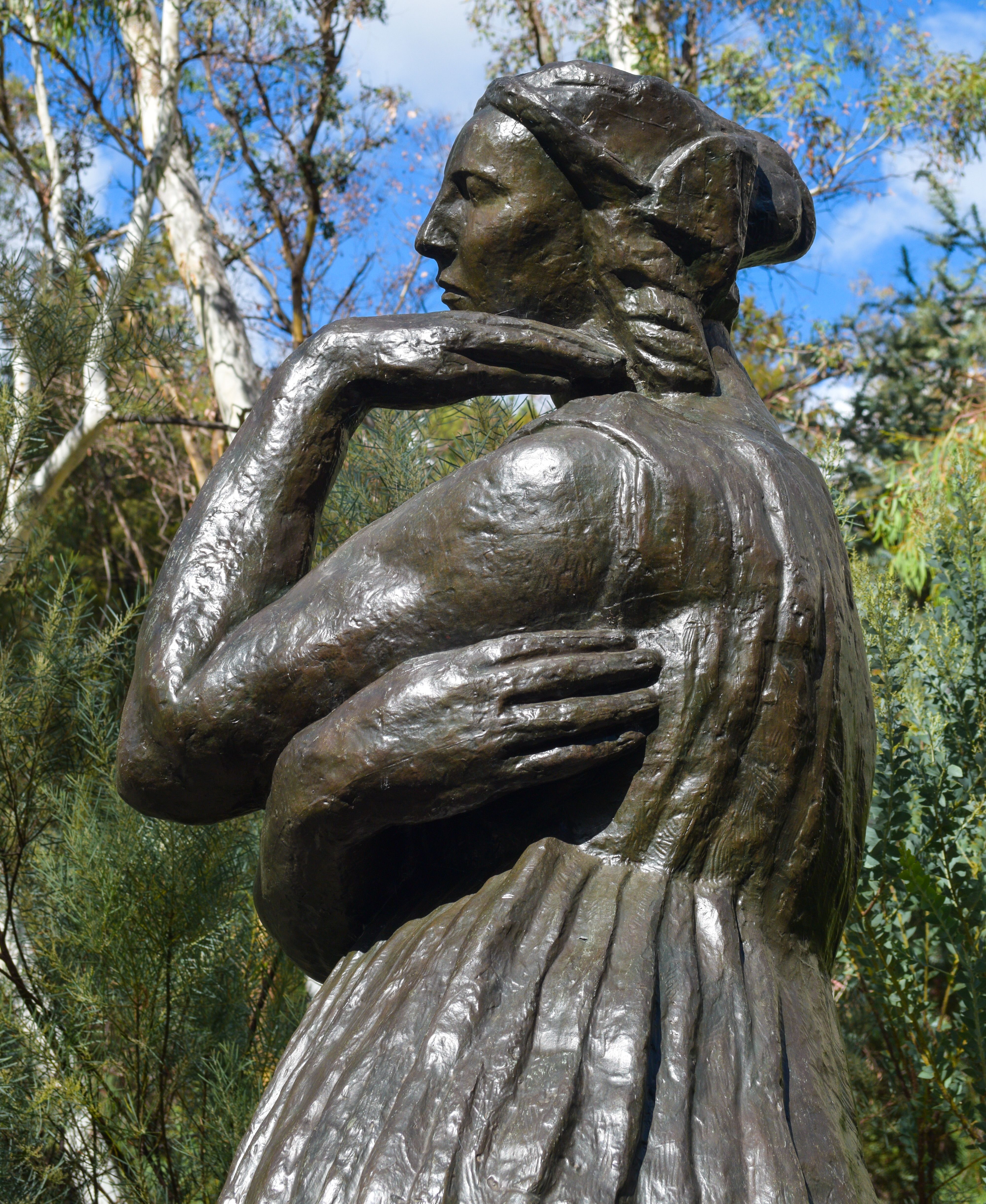 Bronze statue of woman's profile. One hand next to her chin the other embracing herself