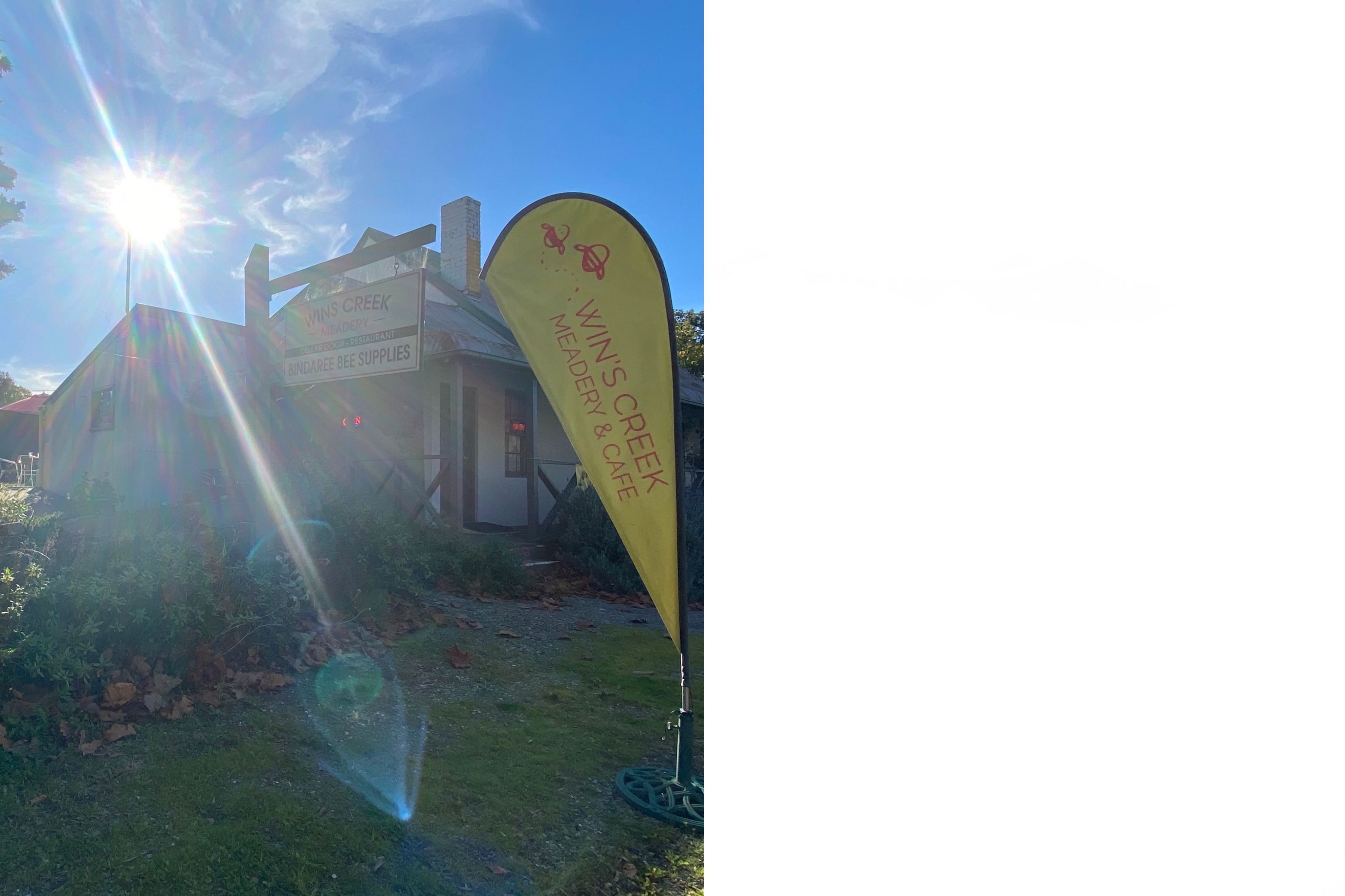 An old style inn with a sign that says "Wins Creek Meadery," the sun shines through, cast light flares across the camera frame.
