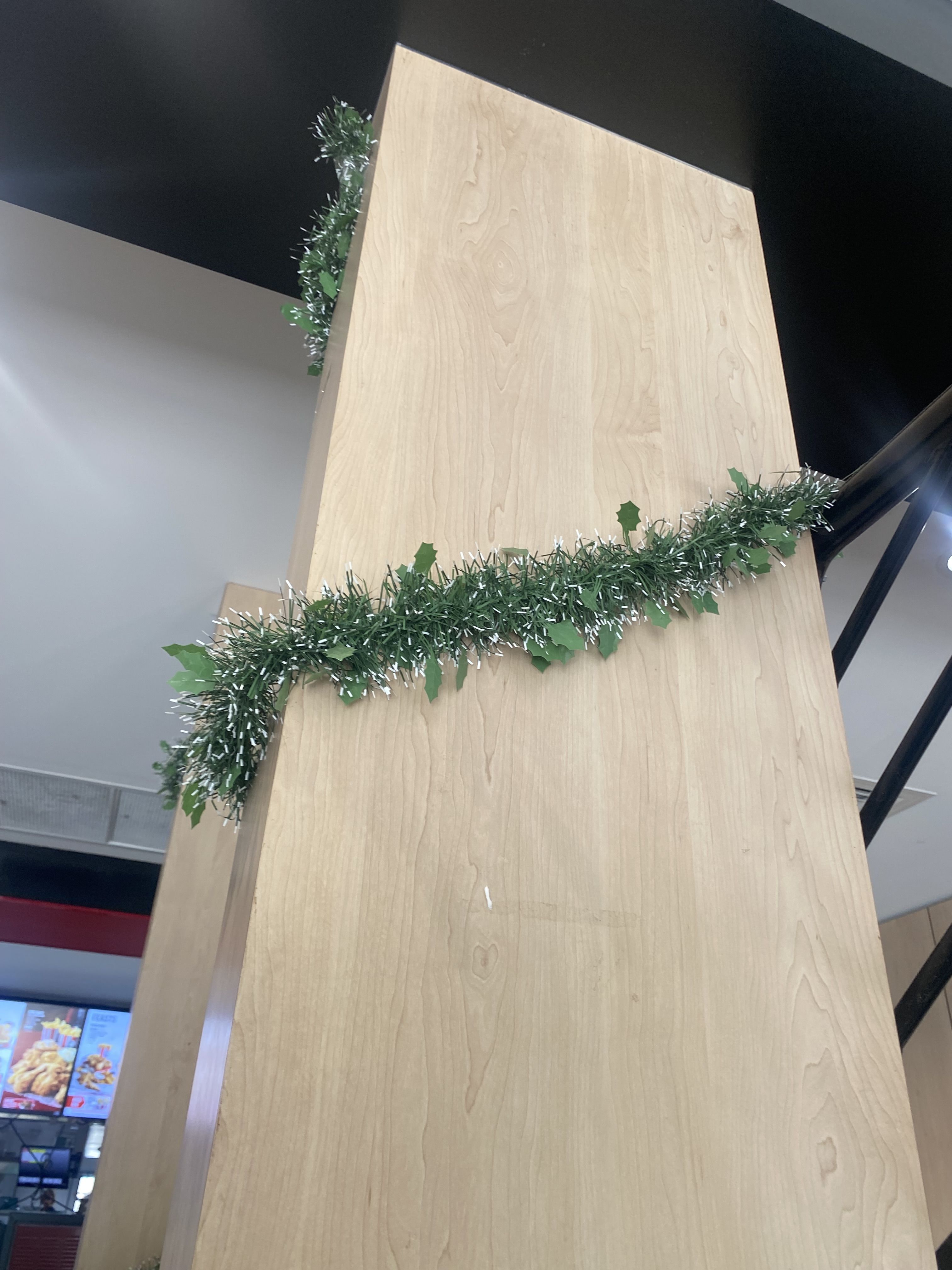 photo of Christmas tinsel wrapping around a pillar in KFC.