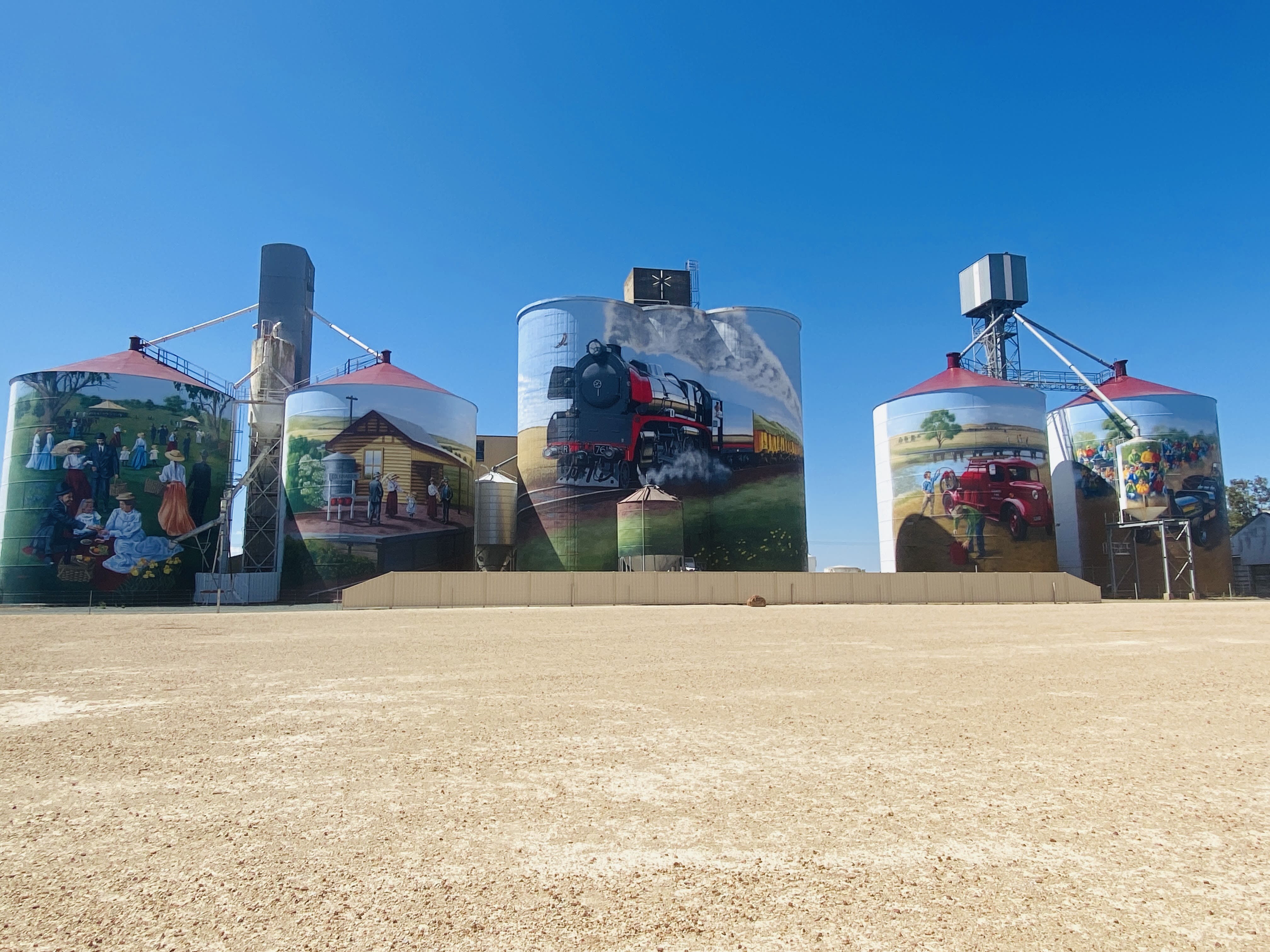 Painted silos showing people picnicking, a train and little town enjoying life, photo by Lila Greyling